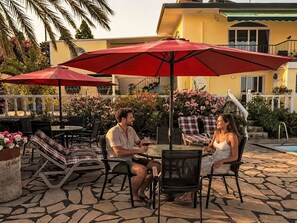 An outdoor patio with a stone floor, red umbrellas, and lounge chairs. - La Palma by Interhome (El Paso)