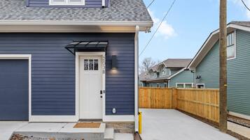 A residential house with a dark blue exterior, a white front door, and a small porch area.