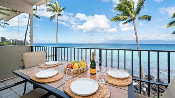 Une table dressée pour le dîner, avec vue sur l’océan et les palmiers.