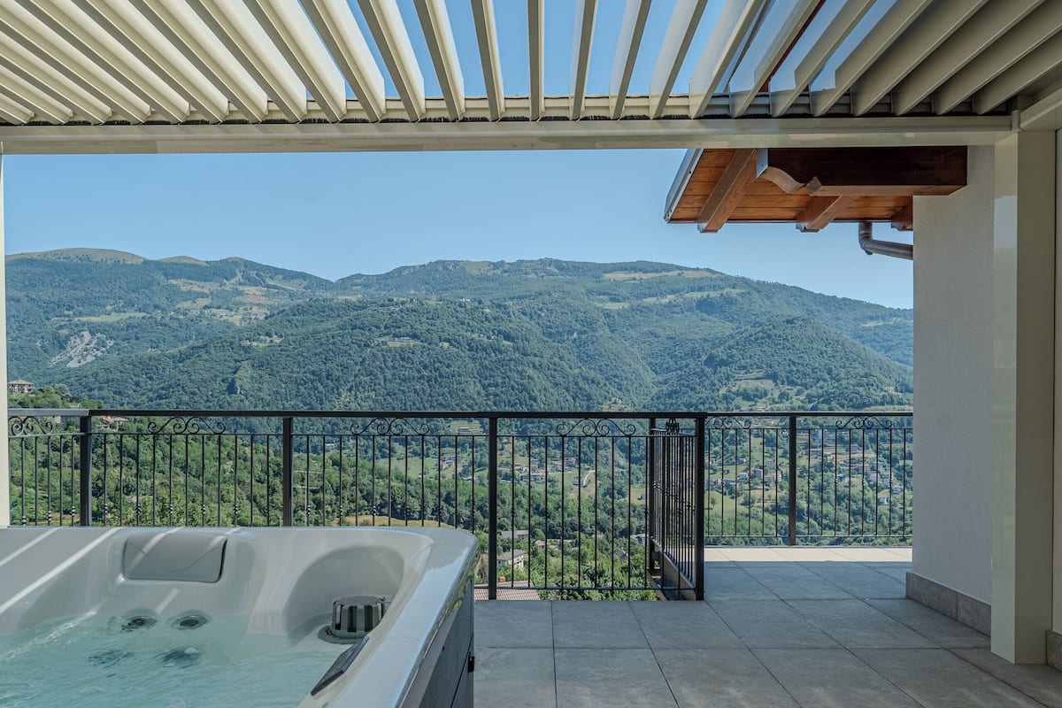 Een bubbelbad op een balkon met uitzicht op de bergen.