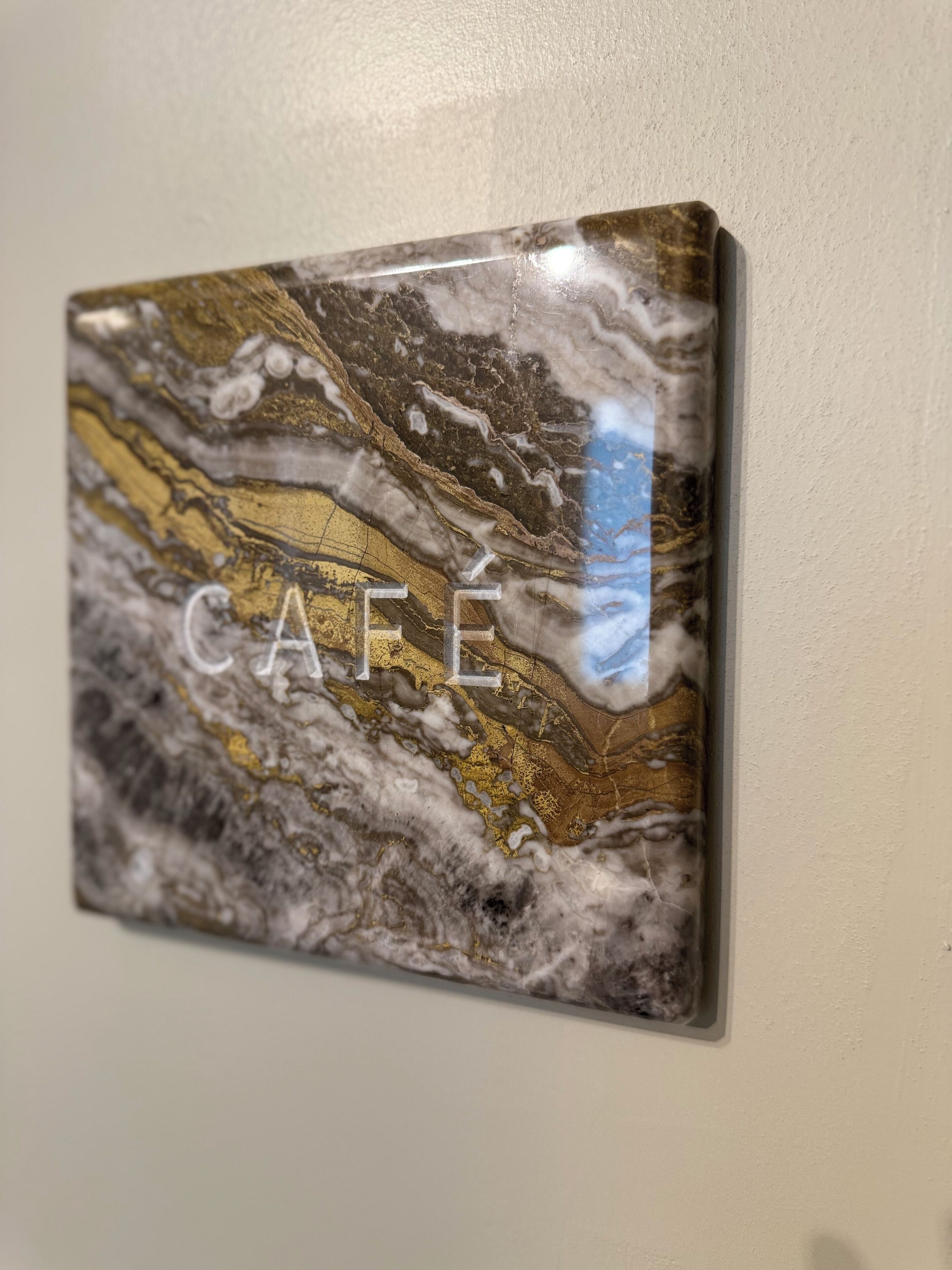 A marble wall art piece with the word "CAFFÉ" on it.