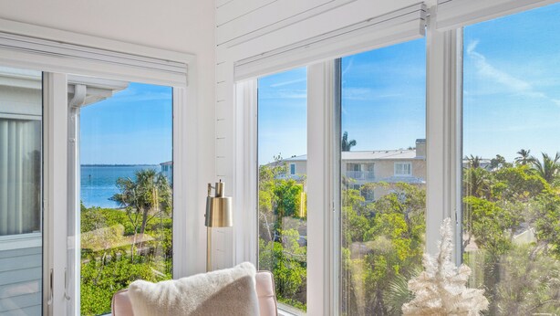 A room with large windows offering a view of the sea and surrounding greenery. - Beautifully Decorated 2 BR Townhome - Cedars East #802 by RVA (Longboat Key)