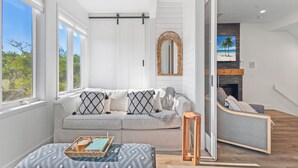 A modern living room with a white sofa, a wooden side table, and a bench with a tray. - Beautifully Decorated 2 BR Townhome - Cedars East #802 by RVA (Longboat Key)