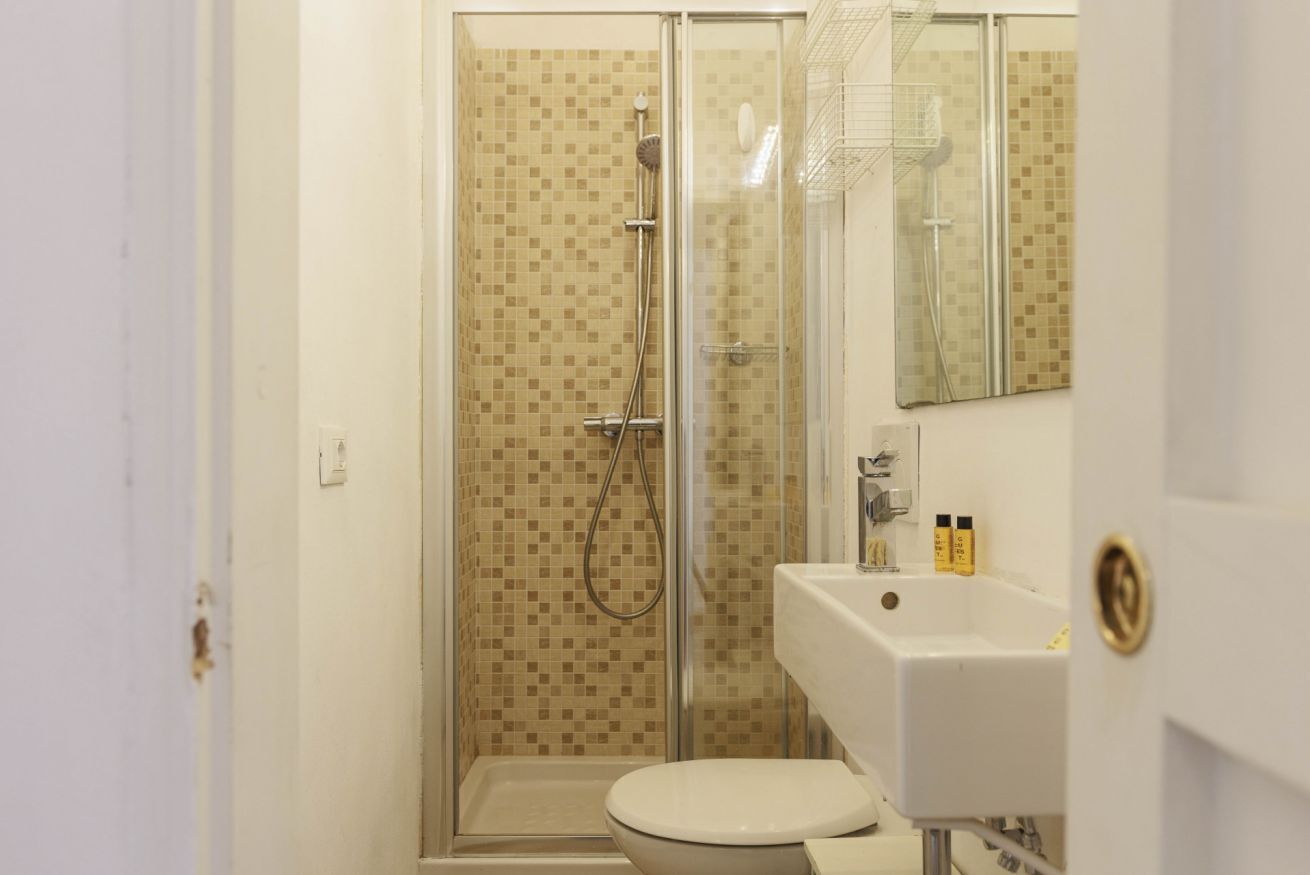 Een badkamer met een douchecabine van glas, een wit wastafelmeubel en een toilet.