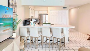 Una cocina moderna con una isla central, taburetes de bar y un refrigerador.