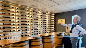 Una bodega con estanterías de madera llenas de botellas de vino y barriles.