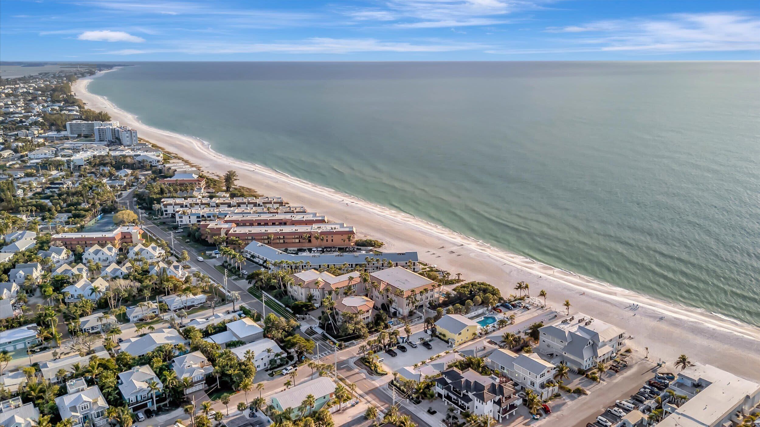 A coastal residential area with beachfront properties, a swimming pool, and a clear view of the ocean.