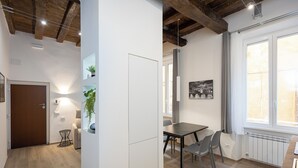 A modern kitchen with a dining area, wooden flooring, and a large window. - Rental in Rome Navona Modern Apartment (Rome)