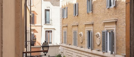 A narrow alleyway with buildings on either side, featuring balconies and shutters.