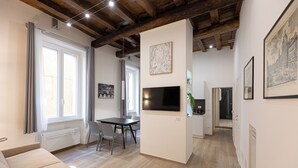 A modern living room with a sofa, dining table, and TV. - Rental in Rome Navona Modern Apartment (Rome)