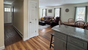 A spacious kitchen with granite countertops and wooden cabinets, a dining area with a wooden table and chairs, and a living room with a leather sofa and a coffee table. - Amazing 3-bedroom home, Full Kitchen, in Newcastle perfect for your getaway (Newcastle)