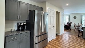A modern kitchen with grey cabinets, a stainless steel refrigerator, and a coffee maker. - Amazing 3-bedroom home, Full Kitchen, in Newcastle perfect for your getaway (Newcastle)