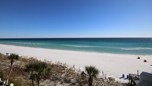 Une plage de sable blanc, avec une eau d’un bleu limpide et quelques palmiers.
