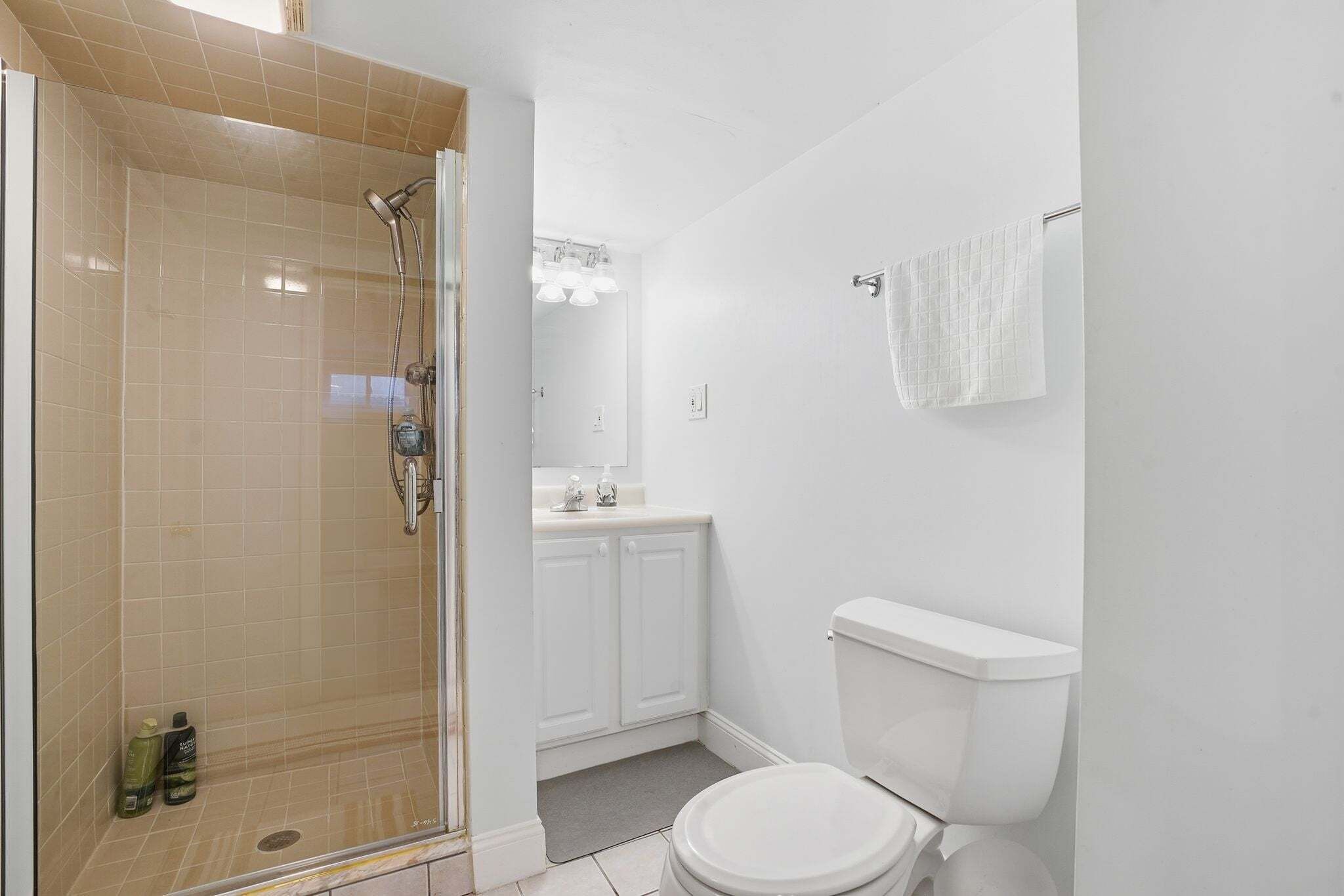 Un baño con ducha envuelta en vidrio, inodoro y lavabo con espejo.