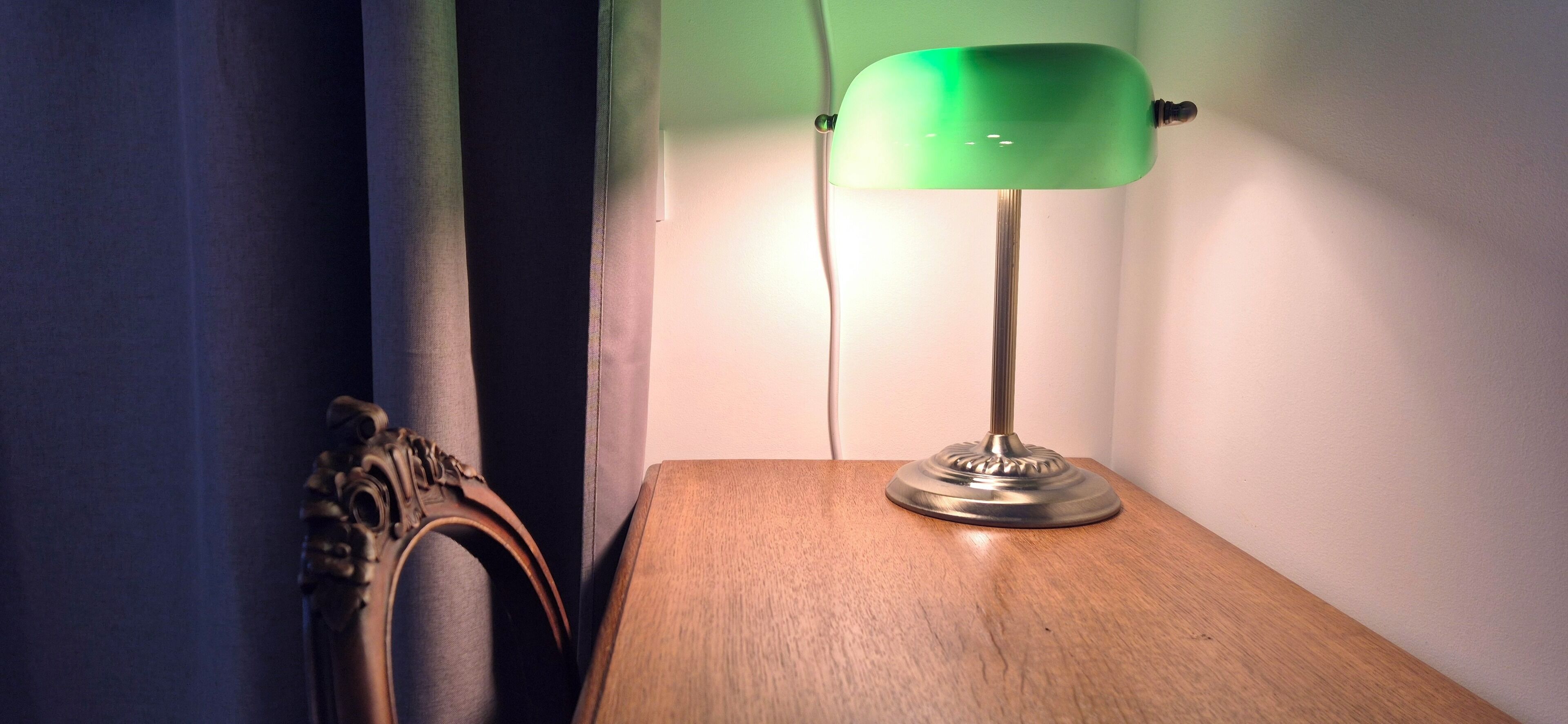 Una lámpara sobre una mesa de madera junto a una cortina.