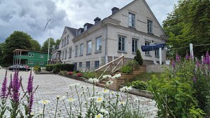 A hotel with a classic architectural style, featuring a prominent entrance with steps and a flagpole. - Slitebadens Annex (Slite)