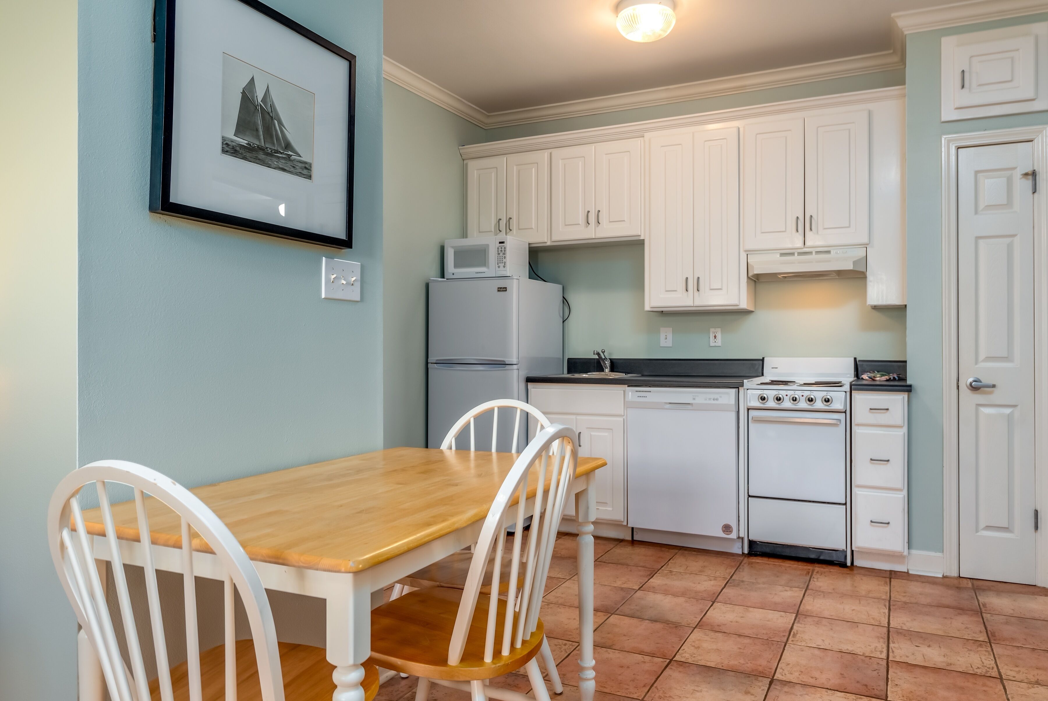 A kitchen with white cabinets, a wooden table, and chairs.