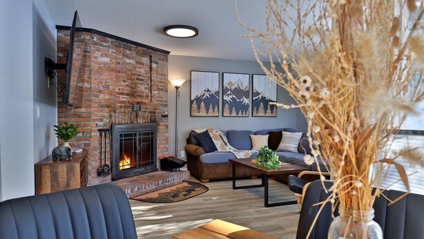 A cozy living room with a brick fireplace, a sofa, and a coffee table. - Fall Line Condo B7 1 Bedroom Home (Killington)