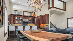 Eine moderne Küche mit Holzausbau, einem Esstisch mit Stühlen und einer Pendelleuchte.
