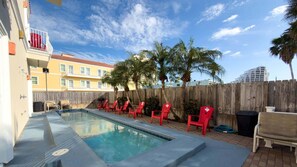A swimming pool with red chairs and a wooden fence. - Pool 1st Floor 75 Yards To Beach Value 2 Bedroom Apts (South Padre Island)