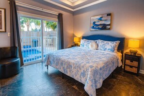 A bedroom with a large bed, a view of a pool through a sliding door, and a painting on the wall. - Pool 1st Floor 75 Yards To Beach Value 2 Bedroom Apts (South Padre Island)
