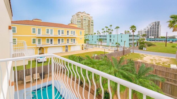 A residential building with a pool, a fenced backyard, and a view of other buildings. - Priced Right Near Beach Well Equipped 2 Bedroom Apts (South Padre Island)