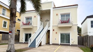A multi-story residential building with balconies, a central staircase, and a gated entrance. - Priced Right Near Beach Well Equipped 2 Bedroom Apts (South Padre Island)