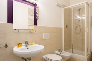 A bathroom with a white sink, a mirror, a toilet, and a glass-enclosed shower.