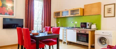 A compact living space with a dining area, kitchenette, and a washing machine.