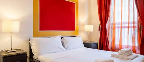 Une chambre d’hôtel avec un grand lit, deux tables de chevet et un mur d’accent de couleur rouge.