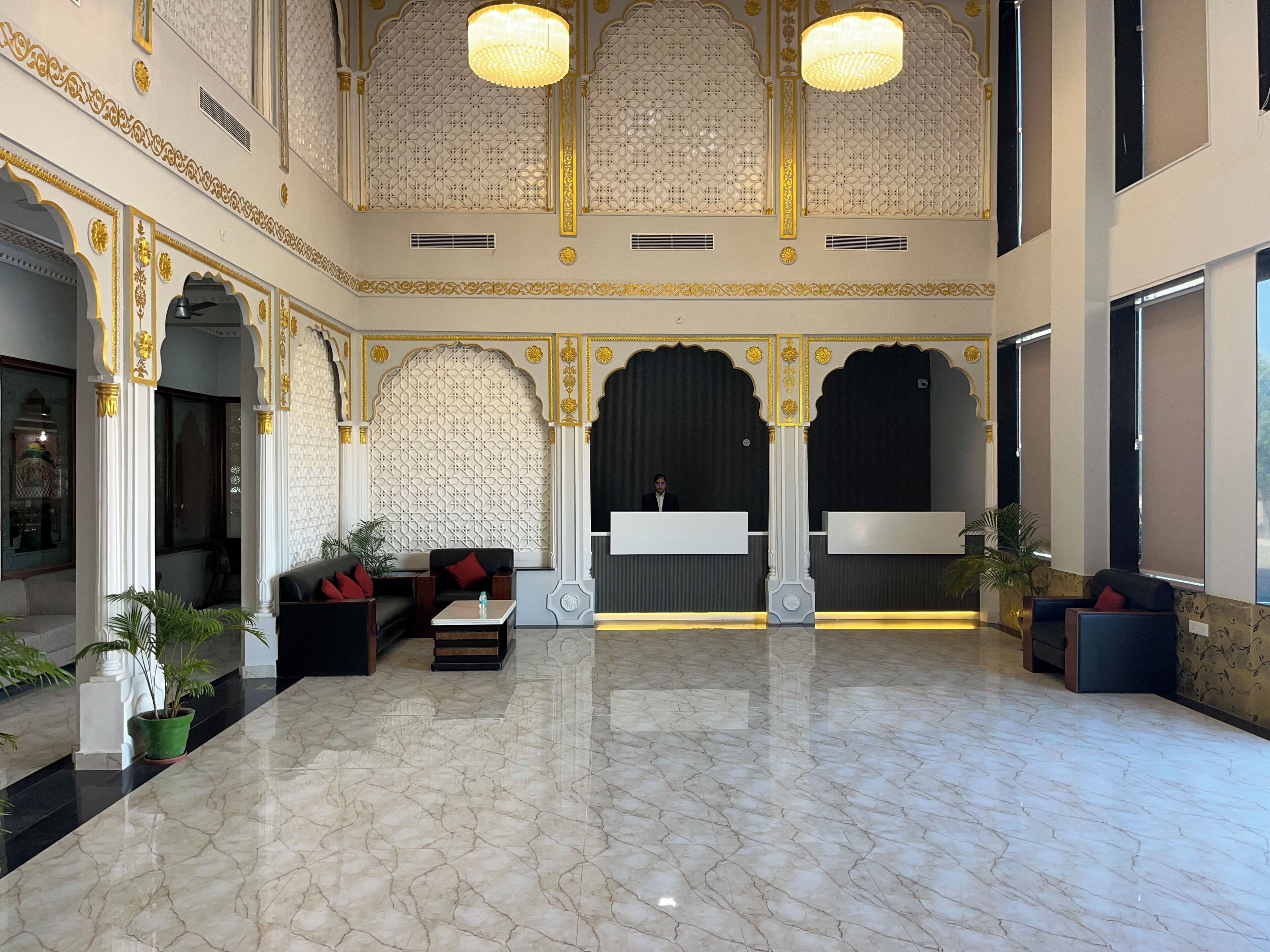 A spacious lobby with marble flooring, ornate arches, and a reception desk.