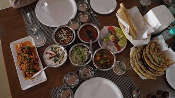 A table set with various dishes, including pasta, rice, and flatbreads, along with multiple glasses and cutlery.