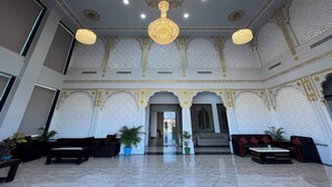 Een ruime lobby met hoge plafonds, sierlijke kroonluchters en gedetailleerde wanddecoraties.