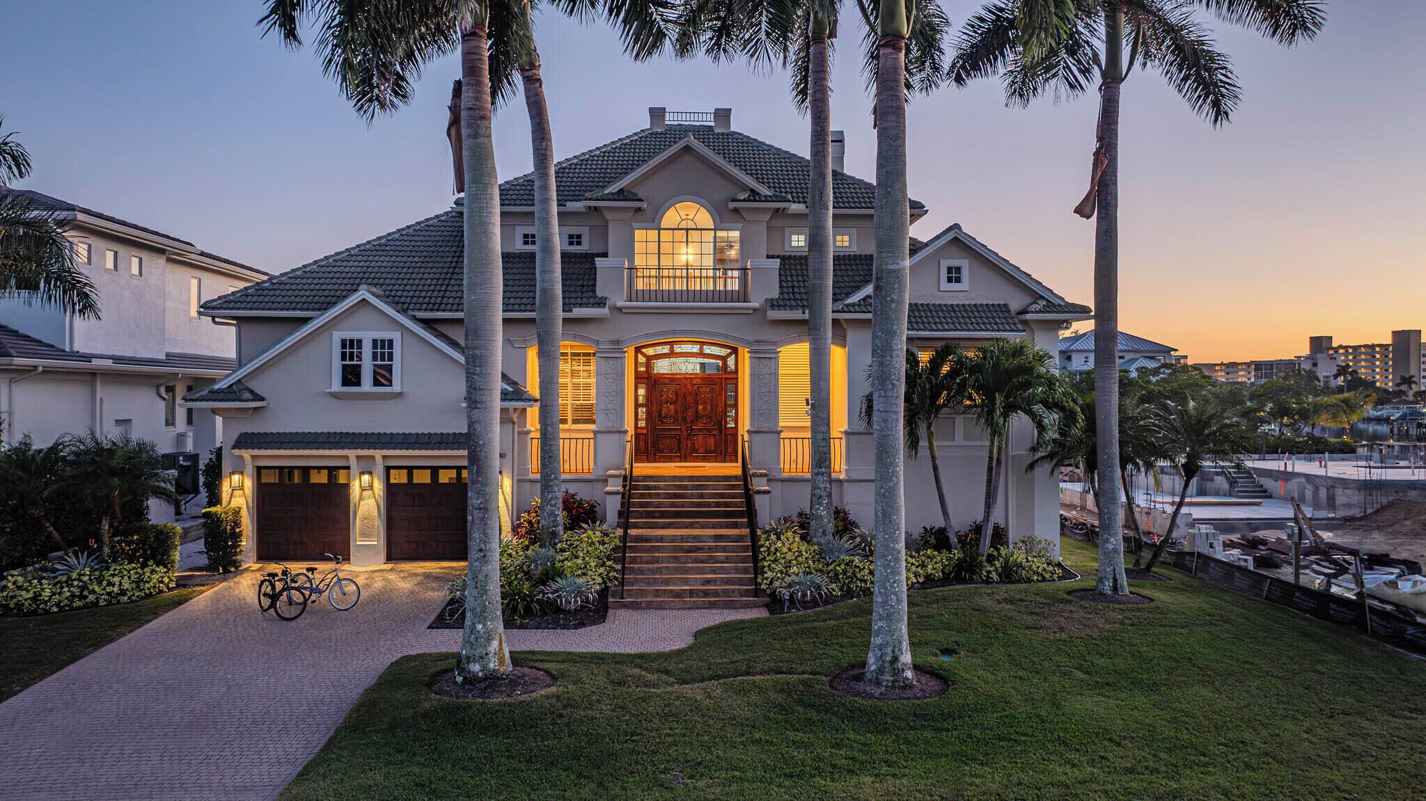 A large, two-story house with a prominent front entrance, a driveway, and a bicycle parked outside.