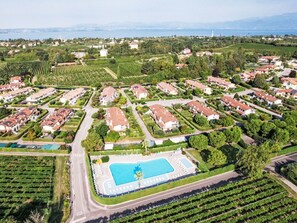 An aerial view of a residential area with houses, a swimming pool, and vineyards. - FeWo C-46 by Interhome (Colà)