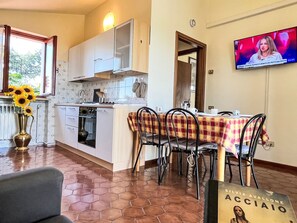 Una cocina con armarios blancos, un salpicadero de azulejos, una estufa y un comedor con una mesa lista para dos.
