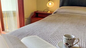 En säng med ett mönstrat överkast, en öppen bok och en mugg med ett kaffemotiv.