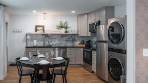 A modern kitchen with a marble countertop, stainless steel appliances, and a dining area with a round table and chairs.