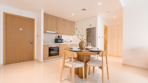 A modern kitchen with wooden cabinets, a built-in oven, and a dining area with a round table and four chairs. - Prime Waterfront Location with Stunning Palm Jumeirah Views, Close to Dubai’s Top Attractions (Dubai)