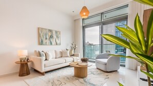 A modern living room with a white sofa, a grey armchair, a round coffee table, and a large window offering a city view. - Prime Waterfront Location with Stunning Palm Jumeirah Views, Close to Dubai’s Top Attractions (Dubai)