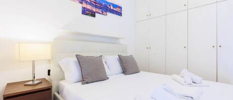 Une chambre d’hôtel avec un lit, une table de chevet, une lampe et une armoire.