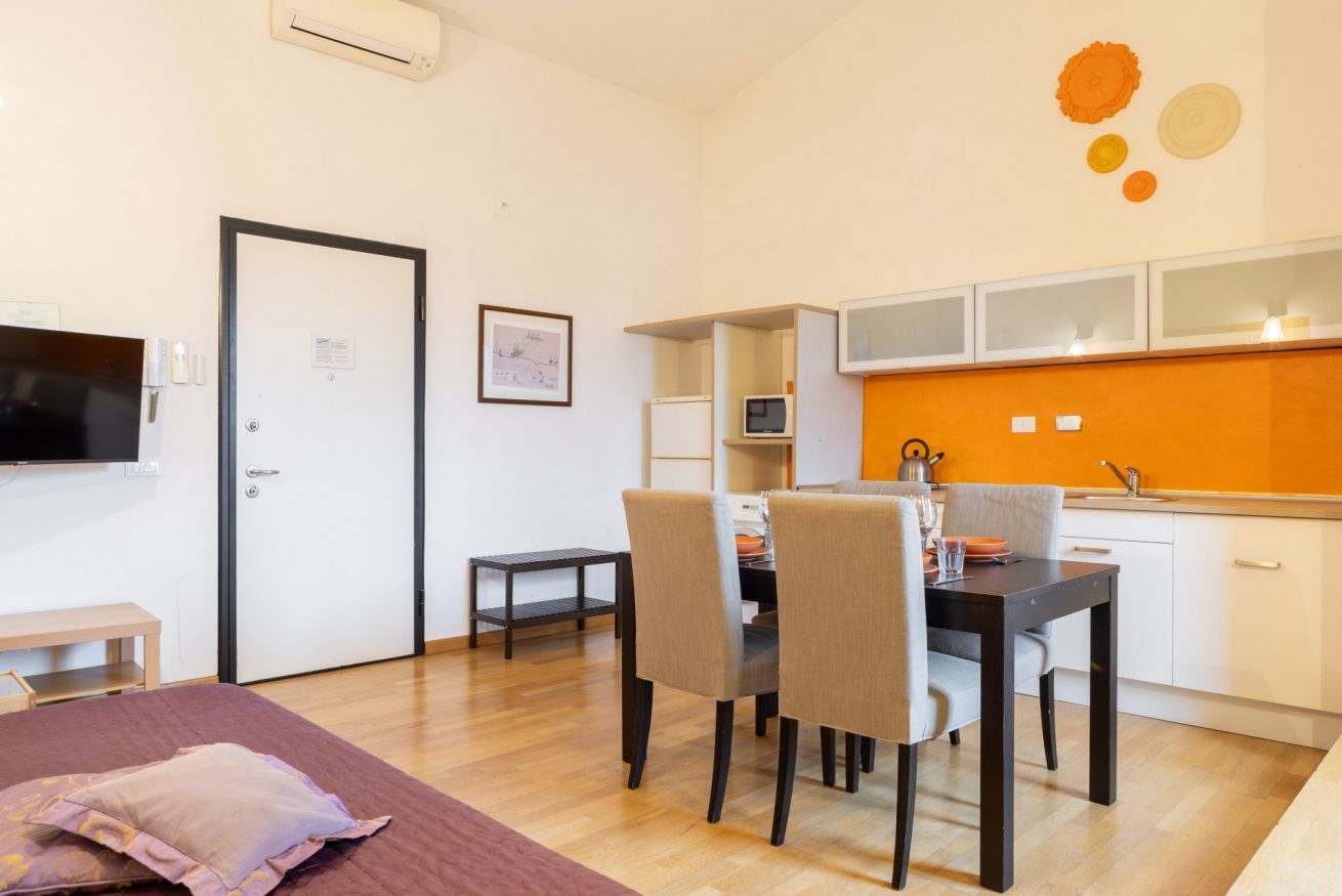 A compact living space with a dining area, kitchenette, and a bed.
