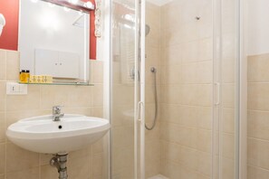 A bathroom with a glass-enclosed shower, a white sink, and a mirror with lights above it. - Sant'Ambrogio Apartments - Raffaello (Firenze)