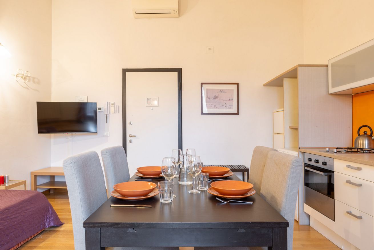 Une cuisine moderne équipée d’une cuisinière, d’un four et d’un coin repas avec une table dressée pour quatre personnes.