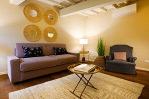 Una sala de estar con sofá, sillón, mesa de centro y espejos decorativos.