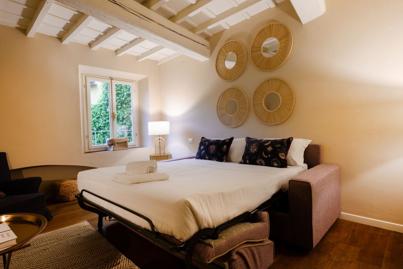 A bedroom with a bed, bedside table, lamp, and wall decor.