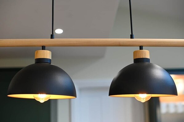 Two black pendant lights with wooden accents hanging from a wooden beam.