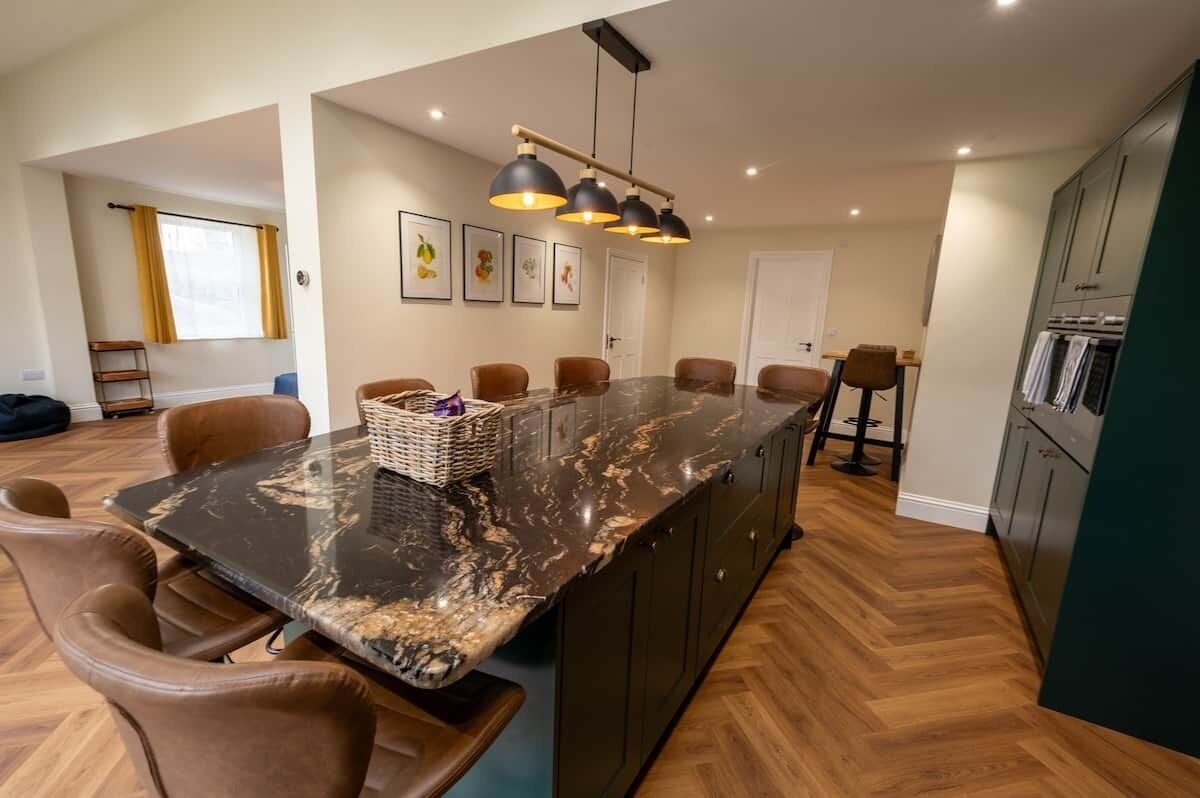 Cocina moderna con una isla central, suelo de madera e iluminación colgante.
