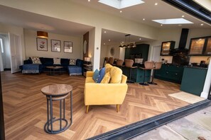 A modern living room with a sofa, a yellow armchair, a round table, and a dining area with chairs.