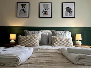 A neatly made bed with pillows, a headboard, and two bedside lamps. - The Nook | Cotswolds Home | HOT TUB | Sleeps 9 (Eastington)